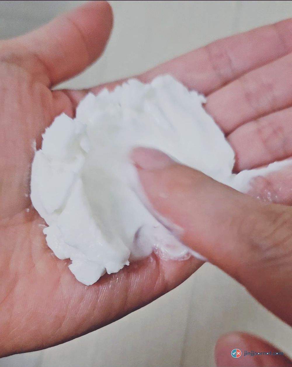 A firm white lump of beplain milk balm sitting on a palm before melting