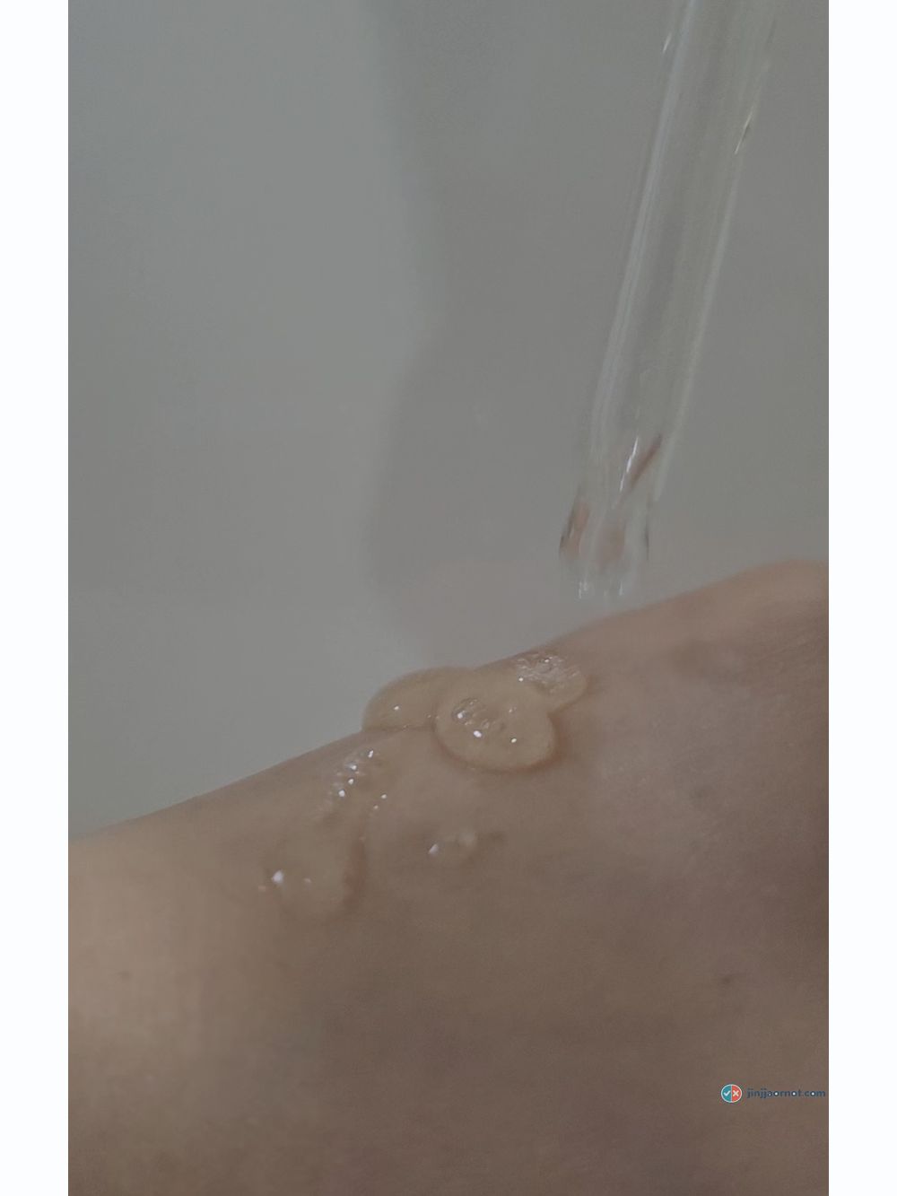 A drop of Beauty of Joseon Glow Serum falling from the dropper onto the back of a hand