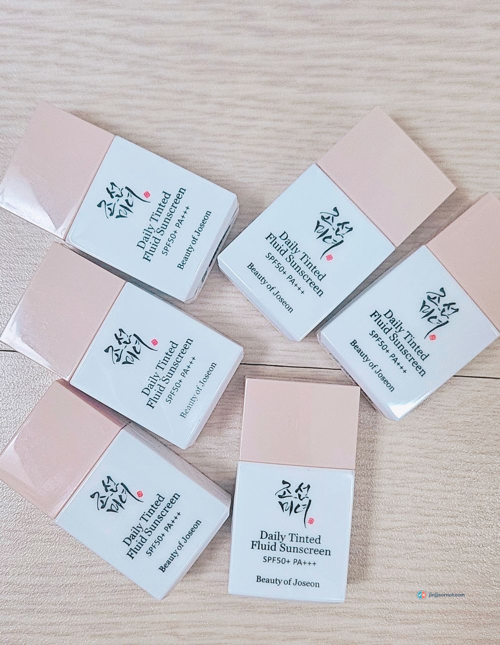 Six Beauty of Joseon Daily Tinted Fluid Sunscreen sample vials laid out on a wooden table