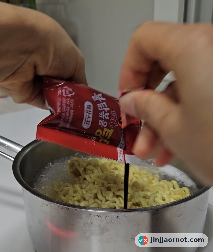 Squeezing the liquid sauce packet into a pot of boiling Buldak noodles
