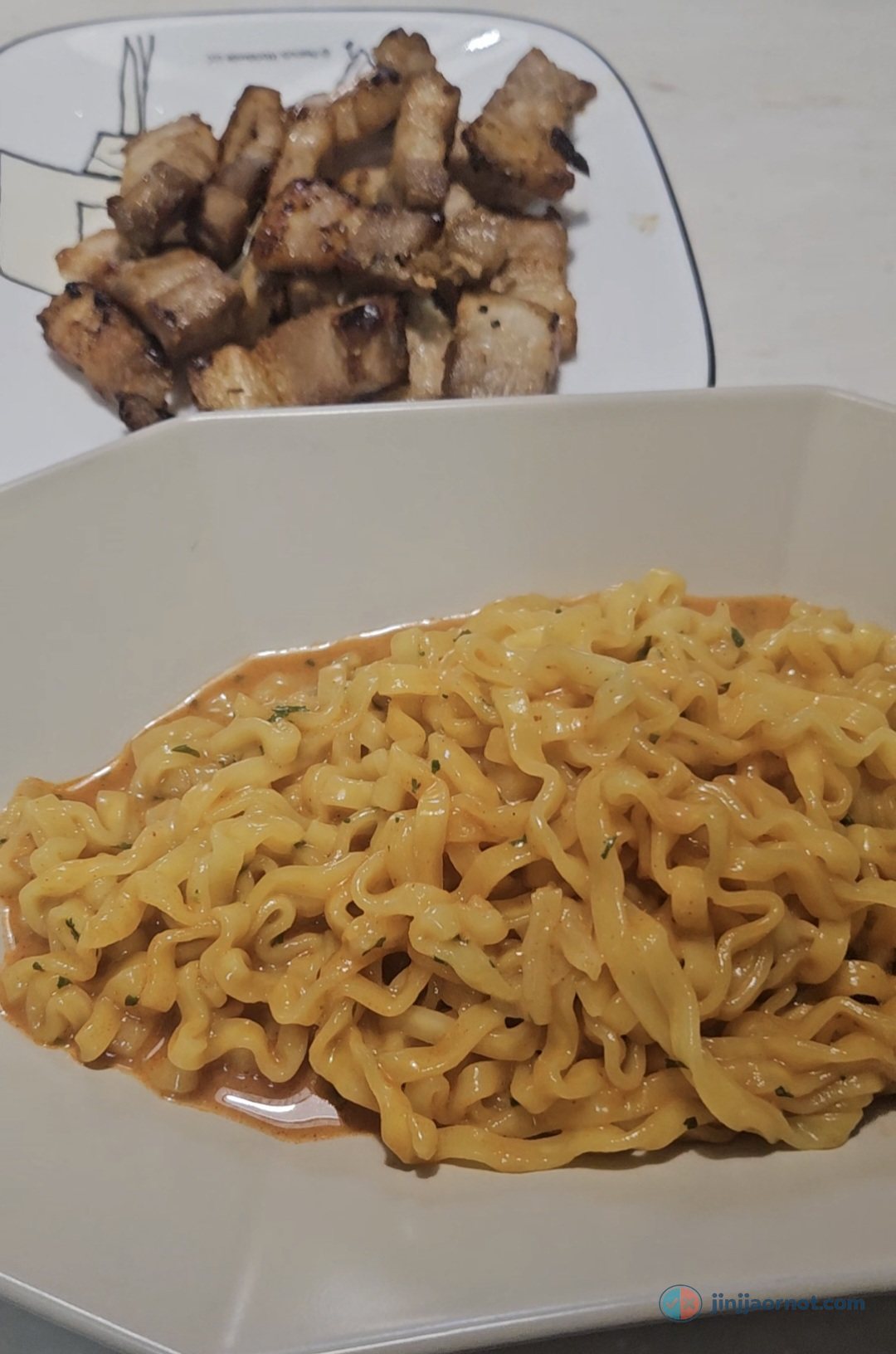 A pot of Original Buldak noodles stir-fried and coated in glossy red sauce