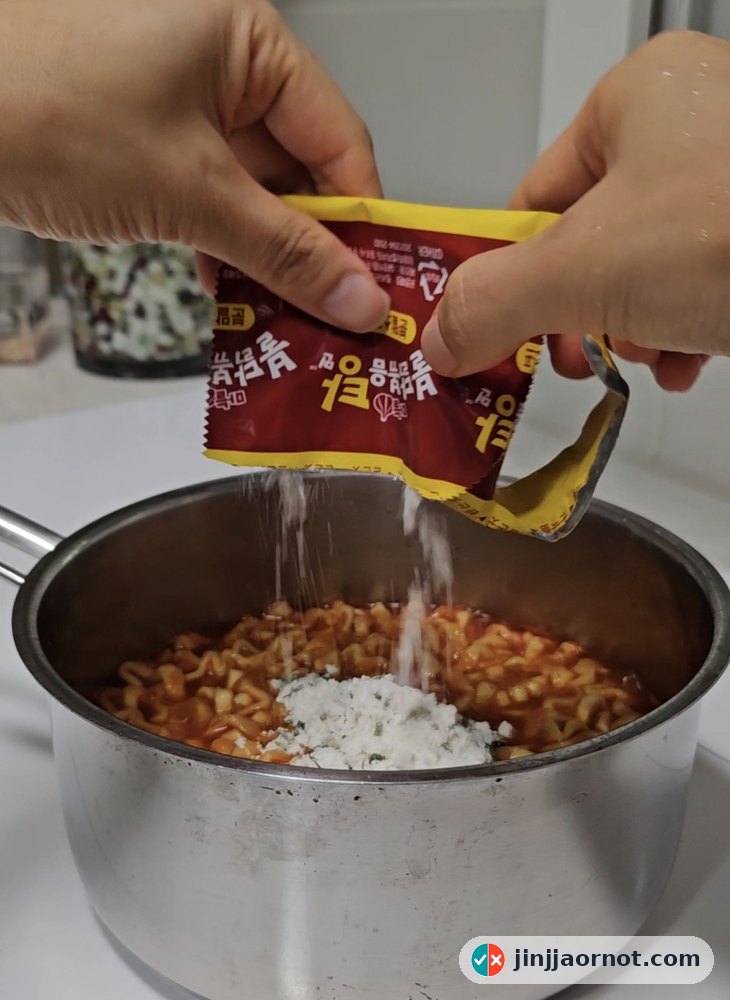 Adding the powdered seasoning packet to Buldak noodles at the end of cooking