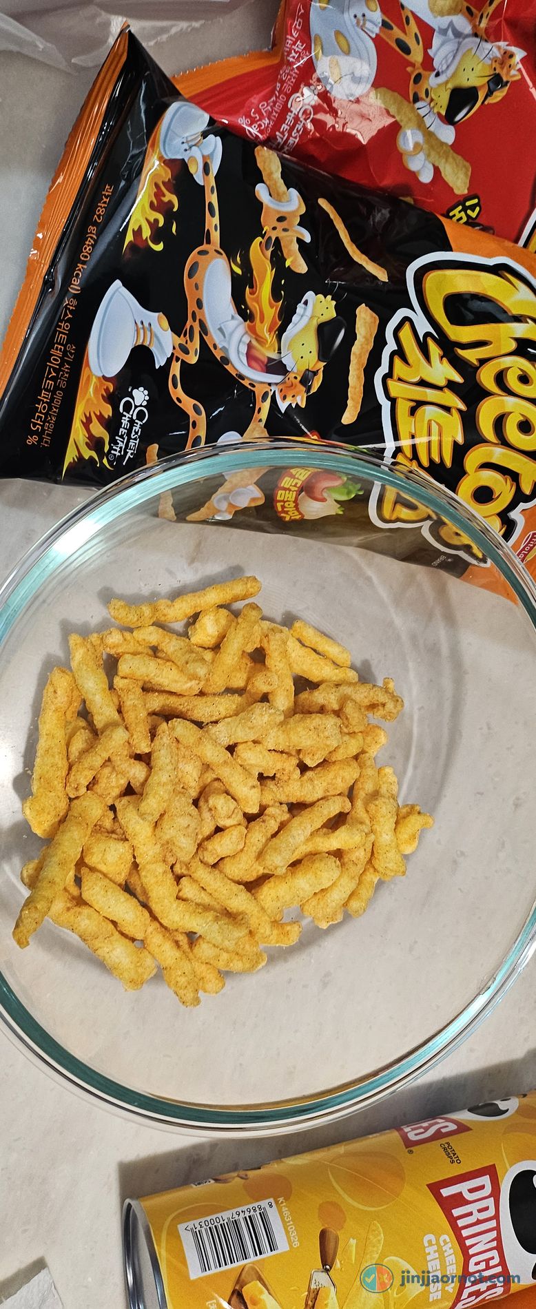 A glass bowl of Korean Spicy Sweet Cheetos poured out, with the black bag showing Chester Cheetah in the background