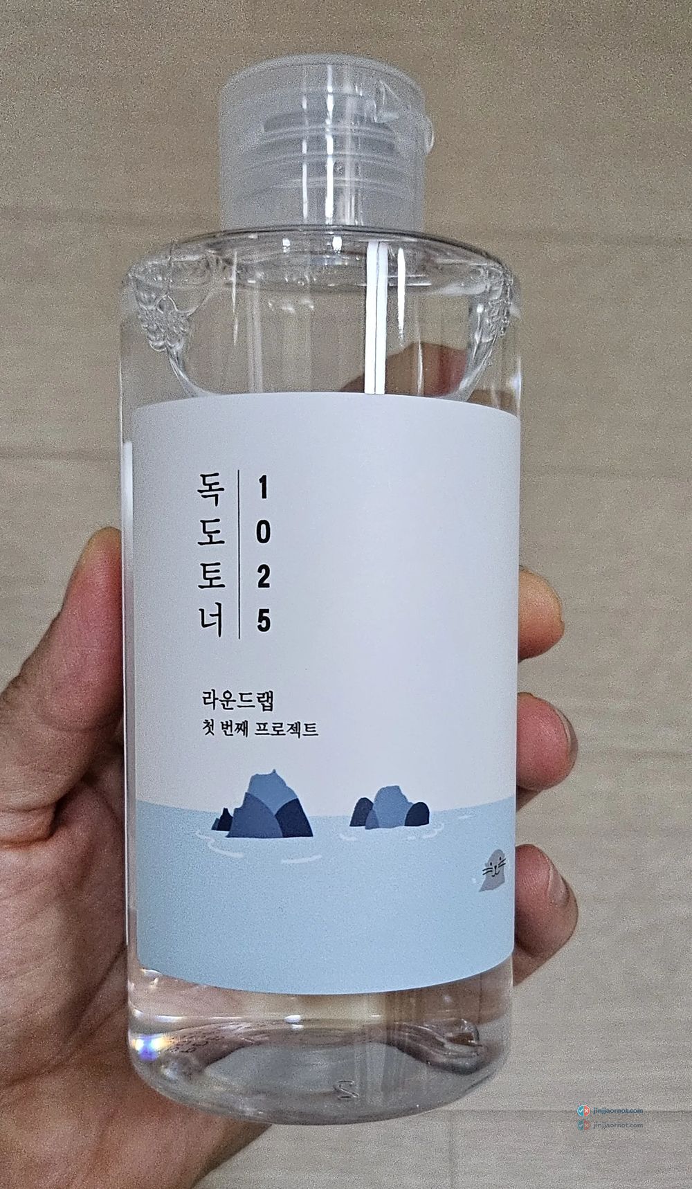 A 200ml bottle of Round Lab 1025 Dokdo Toner held in hand, showing the pale blue label