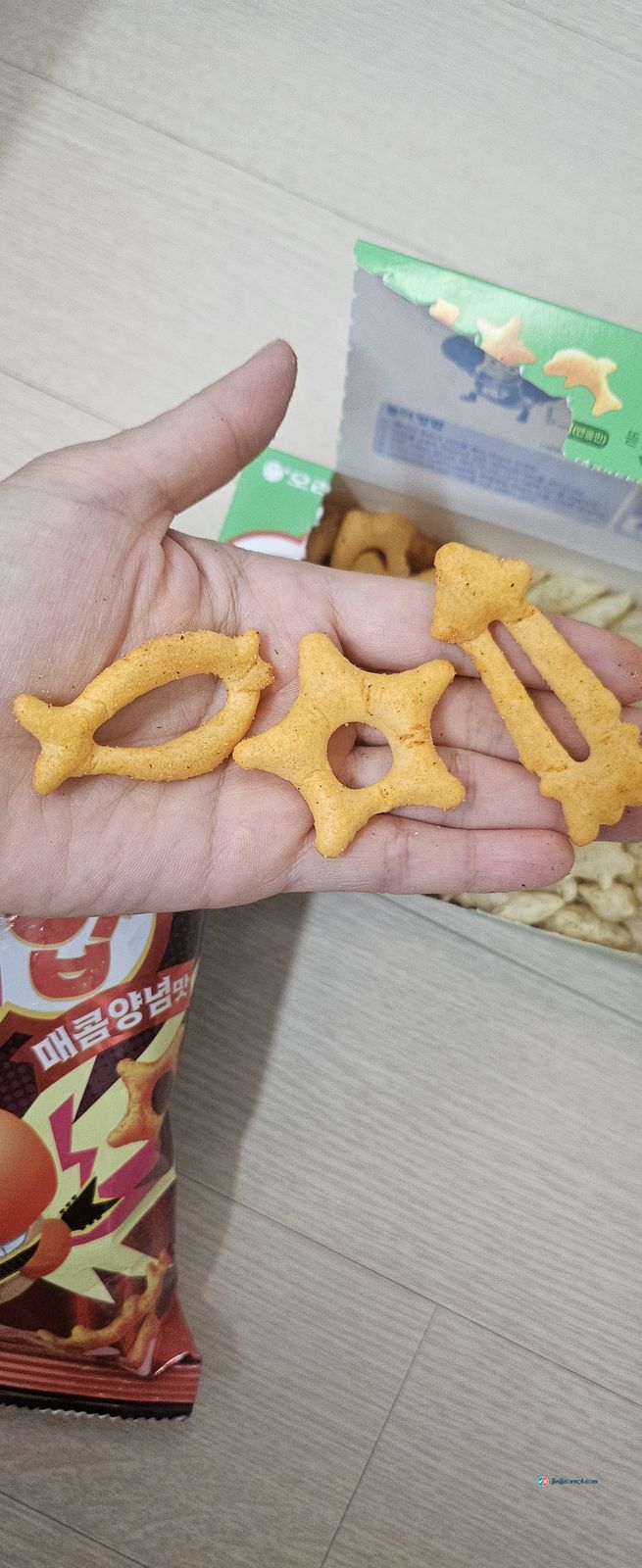 Three Hot Goraebap crackers in a palm, showing the fish, starfish and shape outlines