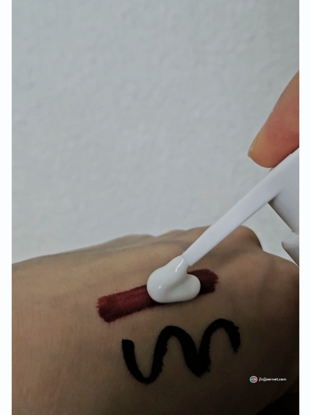 Cleansing milk placed with a spatula onto a straight bar of lip tint drawn on the back of a hand
