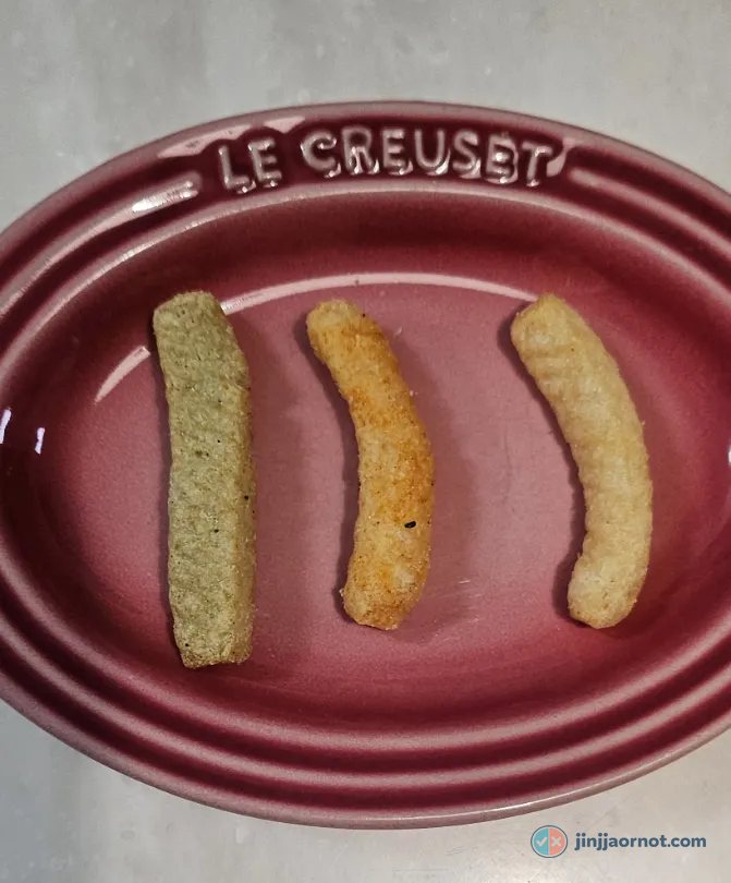Three Saewookkang chips on a pink ceramic plate: green Wasabi on the left, orange Spicy in the middle, pale Original on the right