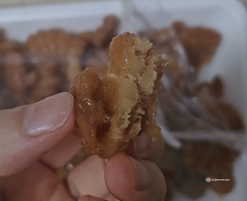 A broken piece of Jangin paji yakgwa held up, showing syrup soaked into the torn open interior