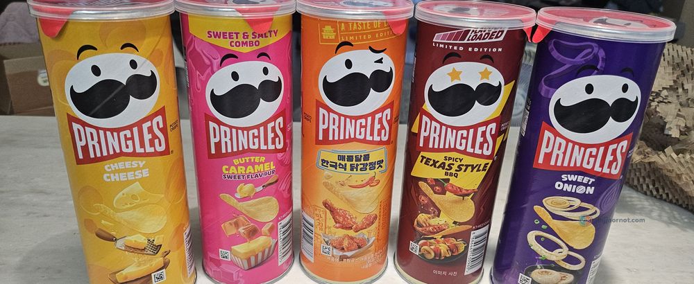 Five cans of Korean Pringles lined up: Cheesy Cheese, Butter Caramel, Korean sweet and spicy chicken, Spicy Texas Style BBQ, and Sweet Onion